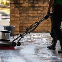 A man worker cleaning the floor with polishing machine